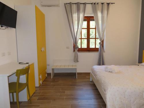 a bedroom with a bed and a desk and a window at B&B Casa Lamanna in Torretta