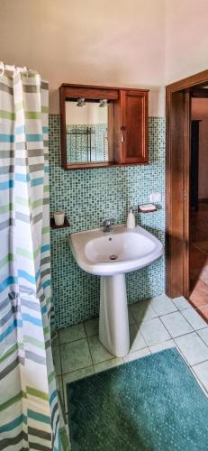 a bathroom with a white sink and green tiles at Liana's home in Gallo