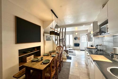a kitchen with a long table and a tv on the wall at Retraite cosy aux portes de la Baie de Somme in Abbeville