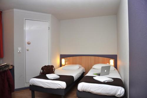 a hotel room with two beds with a laptop on them at Premiere Classe Niort Est - Chauray in Niort