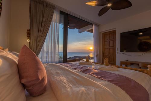 a bedroom with a bed with a view of the ocean at Villa Kinnari in Ko Phangan