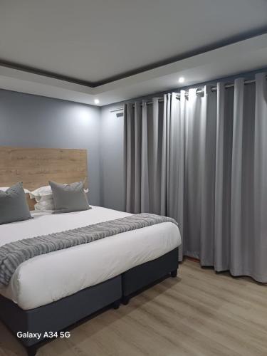 a bedroom with a large bed and curtains at Uptown Apartments - Casalinga Villas in Mataffin