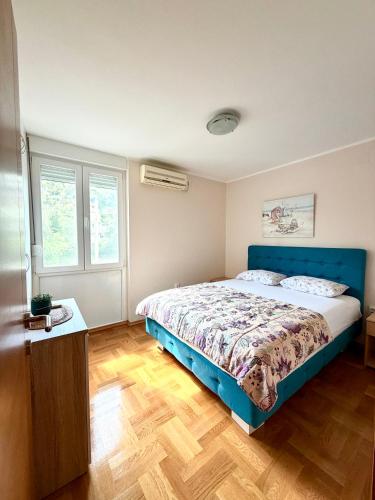 a bedroom with a blue bed and two windows at Pizana Budva Central in Budva