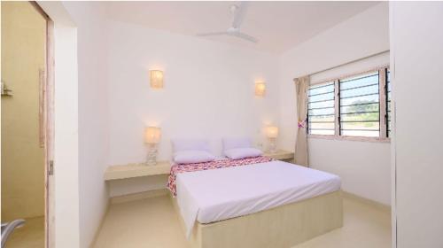 a white bedroom with a bed and a window at Dhahabu Village - Villa 244 Beachfront stay in Mambrui