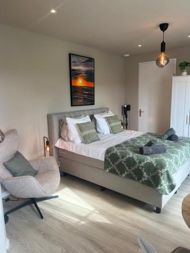 a bedroom with a large bed and two chairs at Etoile aan Zee in Vrouwenpolder