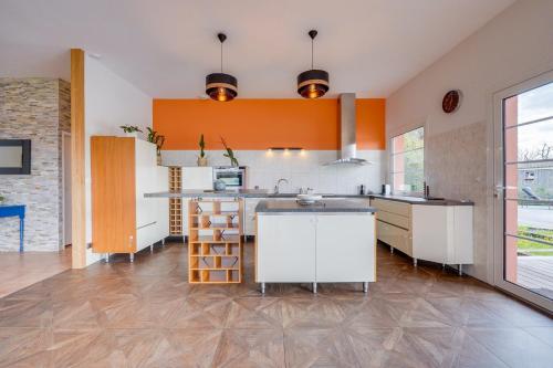 una cucina con pareti arancioni e mobili bianchi di Villa Héloïse a Camblanes-et-Meynac