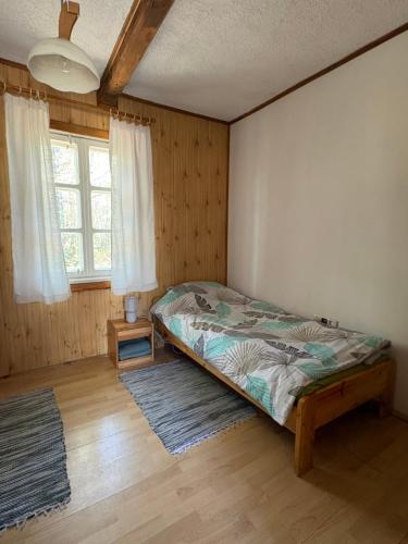 ein Schlafzimmer mit einem Bett, einem Fenster und einem Teppich in der Unterkunft AGRO-CHATKA in Myszyniec