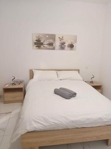 a bedroom with a white bed with two tables at Il-Pitirross Apartment Gozo in Sannat