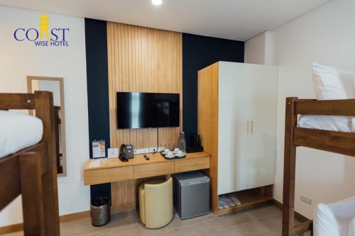 a room with a desk with a tv and a bed at Coast Wise Hotel Dumaguete in Dumaguete