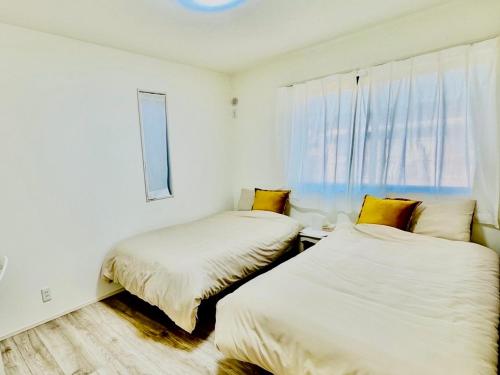 two beds in a white room with a window at Villa 勝浦 in Katsuura