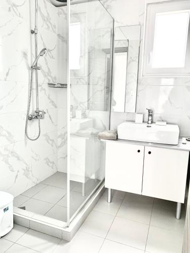 a white bathroom with a shower and a sink at Hayeks Villa private pool near the beach in Daratso