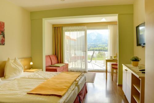a hotel room with a bed and a balcony at Seepark Drobollach in Drobollach am Faaker See