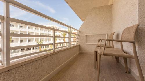 a balcony with a chair and a building at Globales Janeiro in Can Picafort