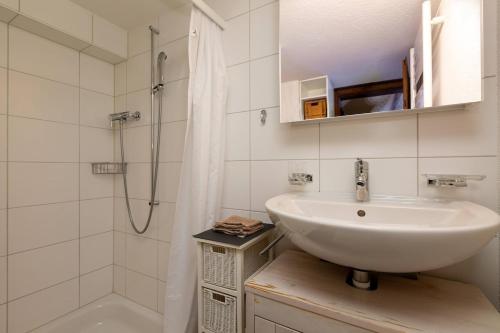 a white bathroom with a sink and a shower at Charming Swiss Lake View studio apartment in Wädenswil