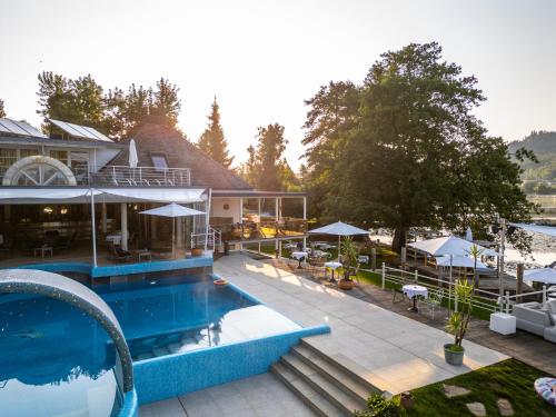 a resort with a pool and tables and umbrellas at Amerika-Holzer Hotel & Resort in Sankt Kanzian