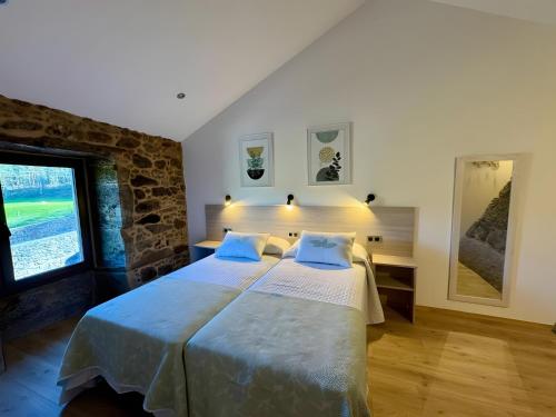 a bedroom with a large bed and a stone wall at Mar Do Val in Muxia