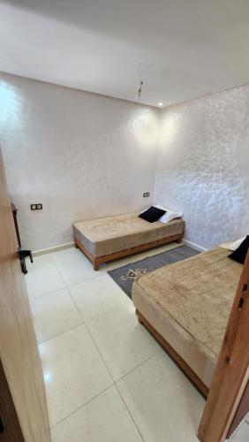 two beds are in a room with a wall at Sidi Rahal in Sidi Rahal