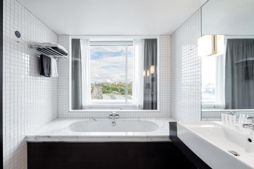 a white bathroom with a tub and a window at Clarion Hotel Stockholm in Stockholm