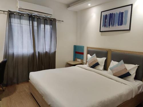 a bedroom with a large white bed and a window at FlxHo Corporate Stays - Udyog Vihar in Gurgaon
