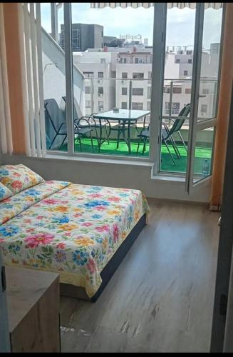 a bedroom with a bed and a table and windows at Shaterovi Gerbera Panoram in Plovdiv