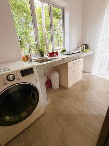 a kitchen with a sink and a washing machine at Solitude in Sri Jayewardenepura Kotte