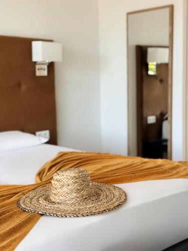 a straw hat sitting on top of a bed at Bella Vista Hôtel, Spa & Gastronomie in Porticcio