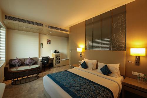 a hotel room with a large bed and a couch at Days Hotel Jaipur Tonk Road By Wyndham in Jaipur