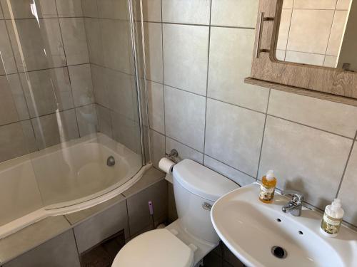 a bathroom with a toilet and a sink and a tub at Sharing living area Apartment in Centurion