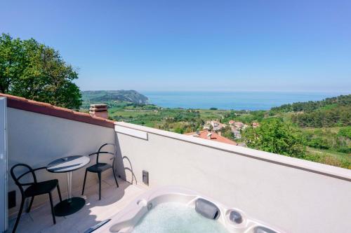 a hot tub on a balcony with a table and chairs at Le Relais du Lierre - Conero Nature Retreat in Poggio
