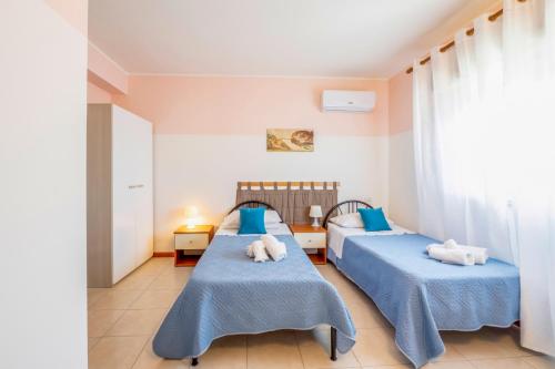 two beds in a room with blue sheets at Il Gabbiano rooms in Donnalucata