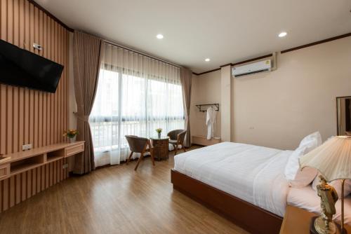 a hotel room with a bed and a desk and a television at Peya Rama-7 Hotel in Bang O