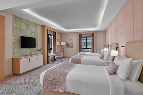 a hotel room with two beds and a flat screen tv at Makarem Haram view suites in Medina