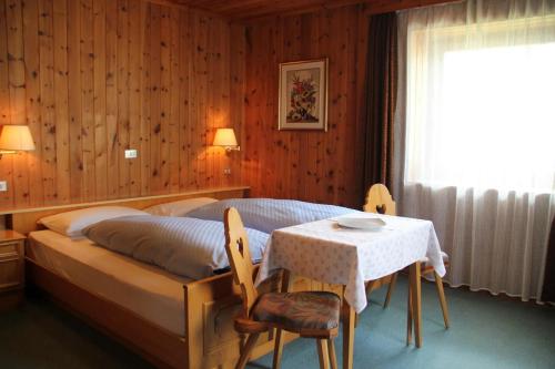 a bedroom with a bed and a table and a window at Garni Villa Linda in Corvara in Badia