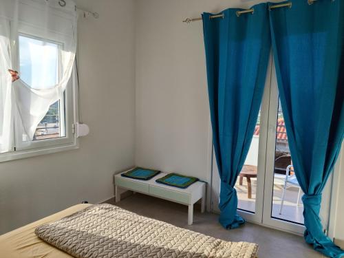 a bedroom with a bed and a window with blue curtains at NMD house in Ermioni