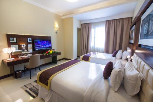 a hotel room with two beds and a desk and a television at Premier Hotel in Manama