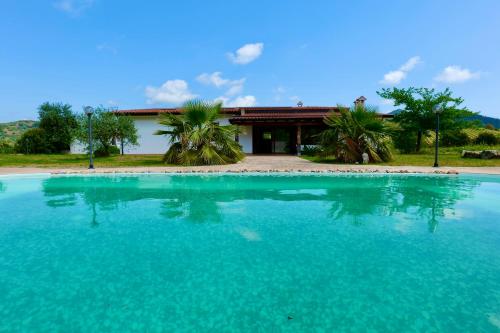 a large pool of blue water in front of a house at Villa IS CARCURIS Jennas in Cardedu