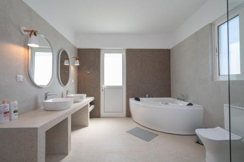a bathroom with two sinks and a tub and mirrors at Thea Luxury Villa in Kos