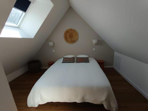 a bedroom with a white bed in a attic at Charmant T2 - 4 couchages à 15mn de la mer in Merlevenez