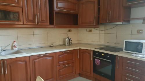 a kitchen with wooden cabinets and a sink and a microwave at Satu Mare Apartments in Satu Mare