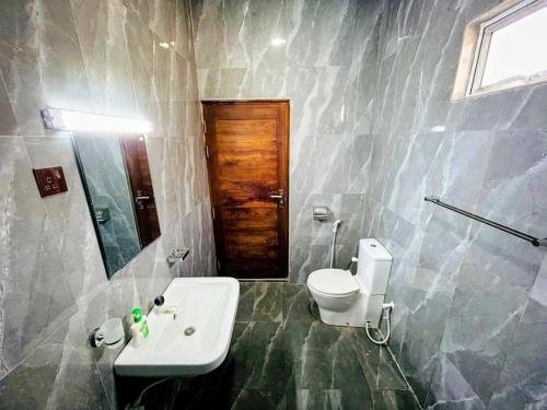 a bathroom with a sink and a toilet and a mirror at Vish Homes in Nallur