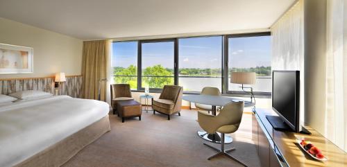 a hotel room with a bed and a desk with a television at Hyatt Regency Mainz in Mainz