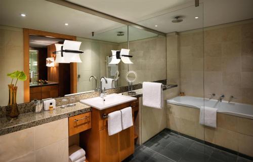 a bathroom with a sink and a tub and a mirror at Hyatt Regency Mainz in Mainz