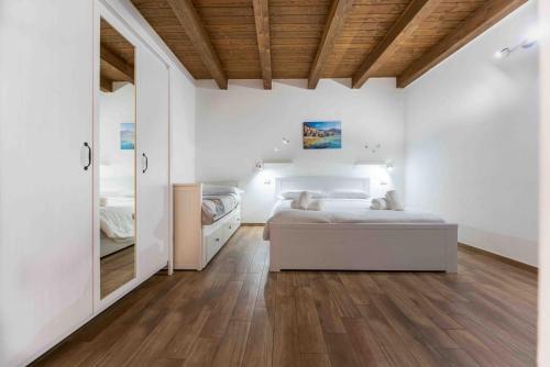 a white bedroom with two beds and a wooden ceiling at Cefalù Center Apartments in Cefalù
