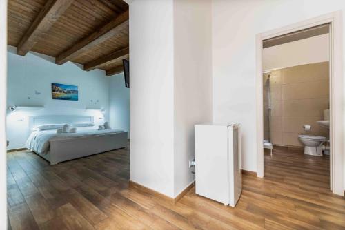 a white bedroom with a bed and a bathroom at Cefalù Center Apartments in Cefalù