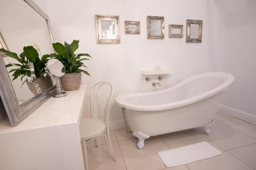 a white bathroom with a tub and plants in it at Brenaissance Wine & Stud Estate in Stellenbosch