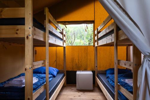 two bunk beds in a room with a window at Safaritent bij speeltuin voor gezinnen op groen rustig park op de Veluwe in Epe