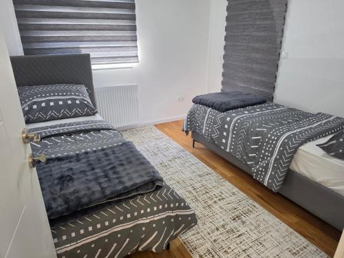 a bedroom with two beds and a chair at Apartman Adria Lux Doboj in Doboj