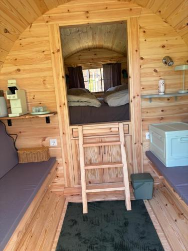a cabin with a bed and a ladder in it at Obstgarten im Warnetal- Campingfass Kobel in Gielde