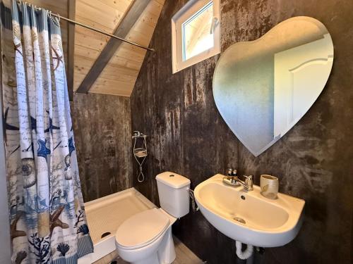 a bathroom with a toilet sink and a heart shaped mirror at Complex Turistic Răsărit Corbu in Corbu