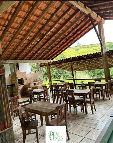 a patio with tables and chairs under a wooden pergola at Bangalô Cachoeira Bem Vinda in Itabirito